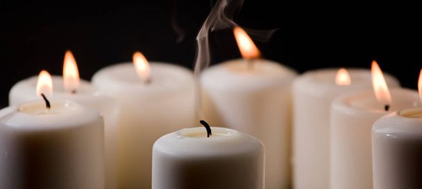 Vela de cera y humo, rodeada de velas con llama ardiente - Foto, Imagen