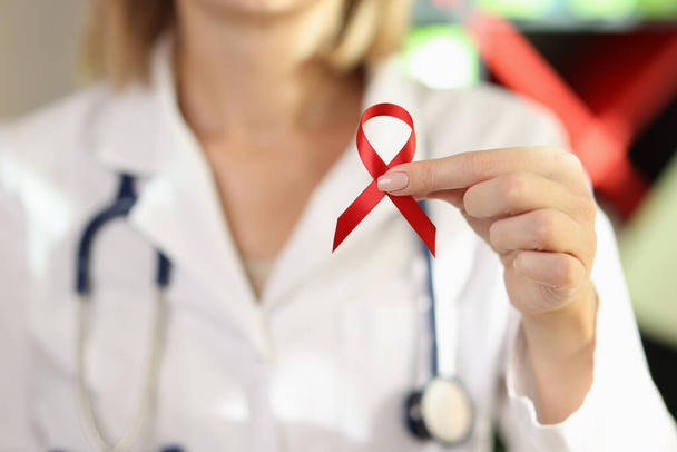 Kobieta doktor trzyma czerwoną wstążkę jako symbol AIDS. Międzynarodowy Światowy Dzień Pomocy, koncepcja świadomości HIV. - Zdjęcie, obraz
