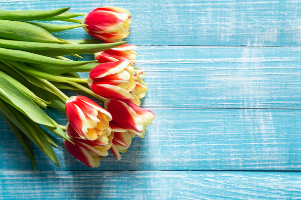 Букет красных и желтых тюльпанов на синем деревянном фоне, вид сверху, пространство для копирования. - Фото, изображение