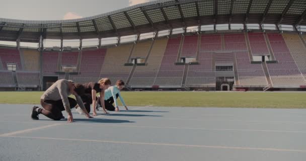 Három fiatal versenyez a futópályán egy üres stadionban. - Felvétel, videó