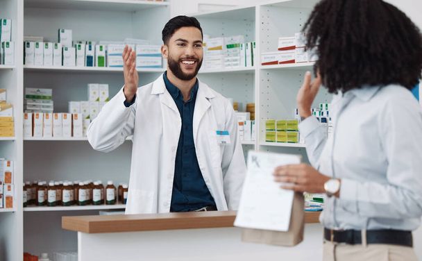 Customer service, counter and pharmacist man with medicine, expert advice or healthcare support. Happy doctor, medical professional or friendly retail person in pharmacy talking to woman at help desk. - Photo, Image