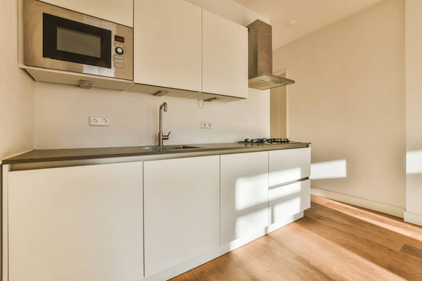 een keuken met witte kasten en apparaten op het aanrecht voor de magnetron, oven en vaatwasser - Foto, afbeelding