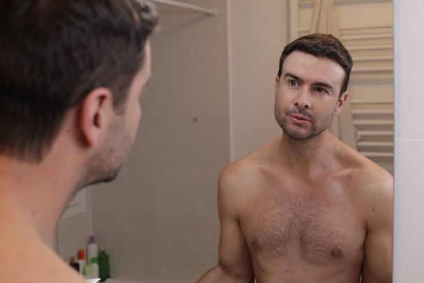portrait of handsome young man in front of mirror in bathroom - Foto, Bild