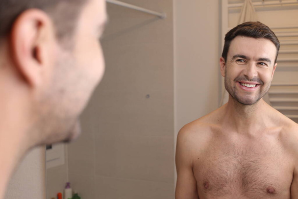 портрет красивого молодого чоловіка перед дзеркалом у ванній
 - Фото, зображення