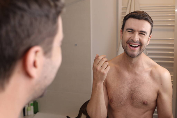 portré jóképű fiatalember előtt tükör a fürdőszobában - Fotó, kép