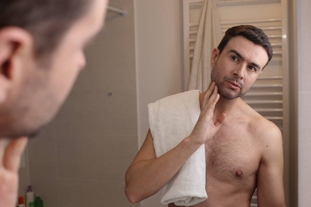 portrait of handsome young man in front of mirror in bathroom - Photo, Image