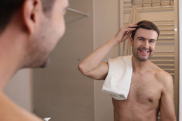 Porträt eines hübschen jungen Mannes vor dem Spiegel im Badezimmer - Foto, Bild