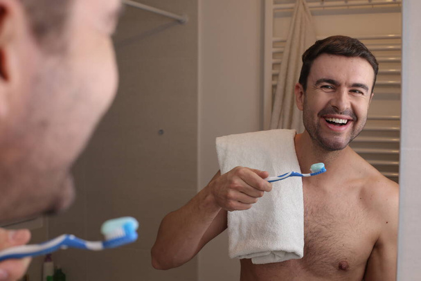 портрет красивого молодого чоловіка чистить зуби перед дзеркалом у ванній
 - Фото, зображення