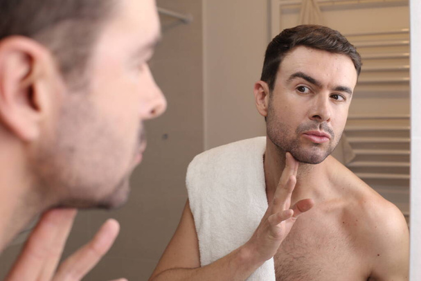 portrét pohledného mladého muže před zrcadlem v koupelně - Fotografie, Obrázek