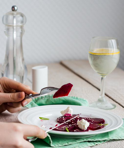 para comer una ensalada de remolacha con queso de cabra, aceite y sésamo, manos
 - Foto, Imagen