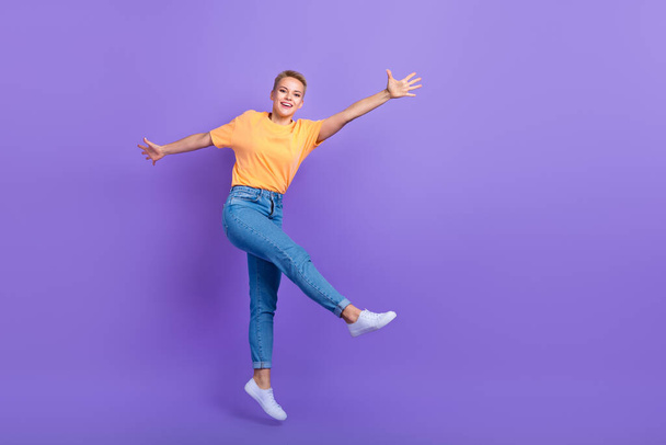 Full length photo of pleasant friendly nice girl jeans white sneakers flying jumping having fun isolated on violet color background. - Fotografie, Obrázek