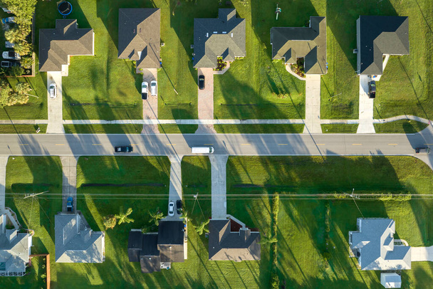 Aerial view of street traffic with driving cars in small town. American suburban landscape with private homes between green palm trees in Florida quiet residential area. - Фото, зображення