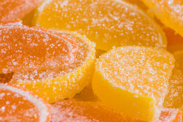 Dekorativní Pozadí žluté a oranžové marmelády ve tvaru klínů citrusových plodů. Želé sladké bonbóny. Struktura jídla. Krásná čtvercová tapeta nebo webový transparent. - Fotografie, Obrázek