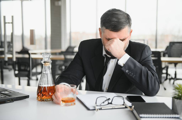 Alcoholism at work. Tired employee drinking alcohol at workplace, can not handle stress. - Foto, Imagen