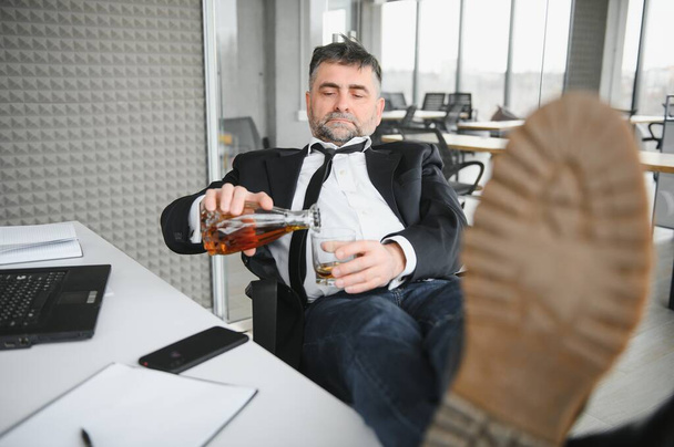 Old businessman drinking from stress - Foto, imagen