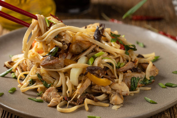 Pasta with chicken in oyster sauce. Prepared in a wok. Served on a plate. - Valokuva, kuva