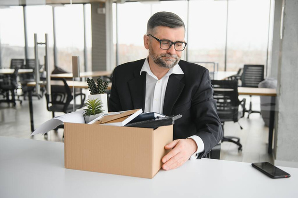Portrait of sad dismissed senior old business man worker taking his office supplies in the box. Pensioner mature retire from work carry staff back home. Lifestyle business retirement, quit job concept. - Foto, Bild