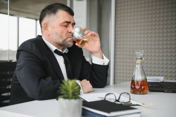 Alcoholism at work. Tired employee drinking alcohol at workplace, can not handle stress. - Foto, Imagem