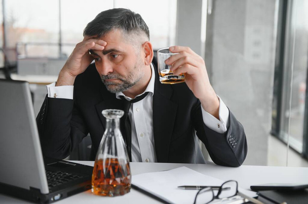 Old businessman drinking from stress - 写真・画像