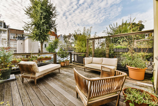 una sala de estar al aire libre con muebles de madera y plantas en maceta en la cubierta, rodeada de cielos azules en el cielo - Foto, Imagen