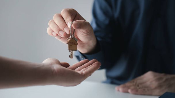 A home rental company employee is handing the house keys to a customer who has agreed to sign a rental contract, explaining the details and terms of the rental. Home and real estate rental ideas. - Fotografie, Obrázek