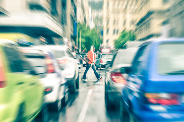 Person überquert die Straße im Berufsverkehr in Kapstadt - Konzept der Verbindung zwischen Menschen und Stau im Vintage-Filterlook - Radial-Zoom-Defokussierung von Pendlerautos auf städtischen Straßen - Foto, Bild