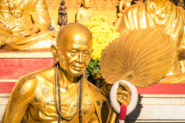 Golden statue of old buddhist monk with flowers ring in the sanctuary of Doi Suthep - Ancient buddha temple in Chiang Mai province in Thailand - Concept of faith and religion in asian countries - Photo, Image