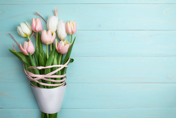 Összetétele rózsaszín és fehér tulipánok, szalagok egy kék fa háttér. Tulipán csokor, tavaszi virágok. Tartalom Születésnapra, Valentin napra, Nők Napjára. Lapos fekvés, felülnézet, közelről, másolás - Fotó, kép
