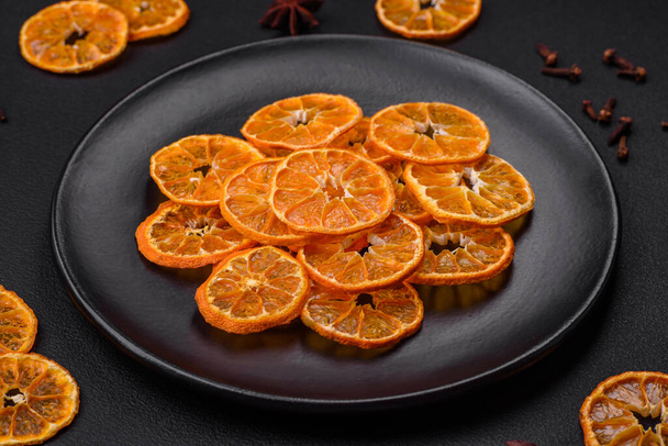 Fette di mandarino arancio brillante di forma rotonda essiccate su uno sfondo materico scuro - Foto, immagini
