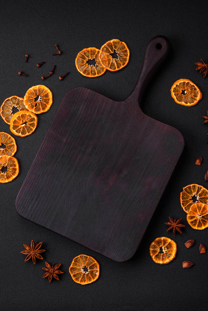 Висушені круглої форми скибочки яскраво-помаранчевого кольору мандарина на темному текстурному фоні
 - Фото, зображення