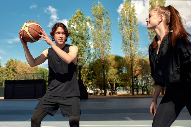 Primer plano de los jóvenes que juegan baloncesto, chicos y chicas que juegan baloncesto en un día soleado, dedicando activamente tiempo. - Foto, Imagen
