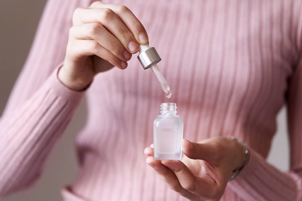 Young woman holding a bottle of essential oil and dropping a drop - Photo, Image