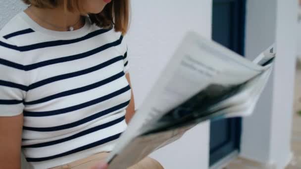 Kézen fogva a reggeli újságokat. Fókuszált turista lány olvasás magazin keres bérleti ajánlatok szabadban. Gyönyörű komoly nő ellenőrizze a napi pénzügyi ingatlan híreket. Reggeli szabadidő koncepció - Felvétel, videó