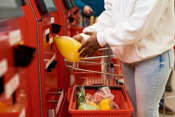 Consumatore donna nella scansione casualwear prodotti alimentari scelti nel terminale self sesrvice mentre acquista bevande, frutta e verdura - Foto, immagini