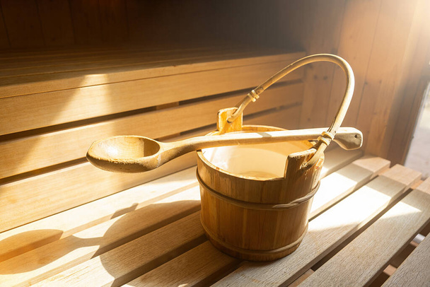 Wiadro wody z drewnianą łyżką do wylewania wody na gorące kamienie w fińskiej saunie, spa i ciepłej kąpieli terapeutycznej obraz koncepcyjny. - Zdjęcie, obraz