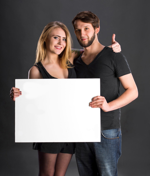 Sorridente coppia tenendo grande scheda bianca vuota
 - Foto, immagini