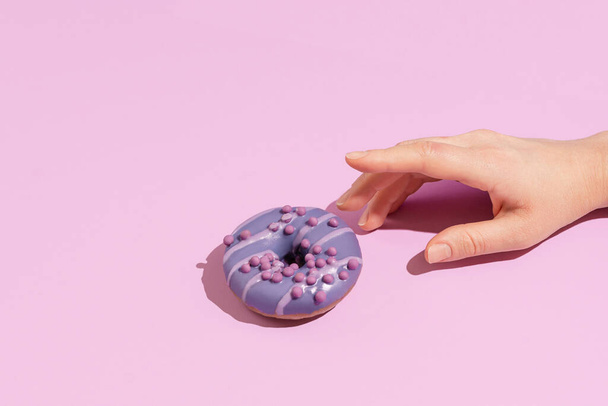Uma mão com um saboroso donut em um fundo de cor - Foto, Imagem