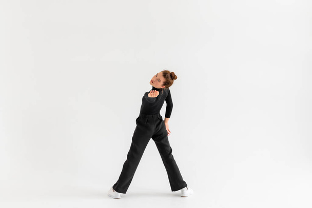 若い女の子,プロのヒップホップダンサーで黒の服は、コピースペースがたくさんある隔離された白い背景の上に実行. - 写真・画像