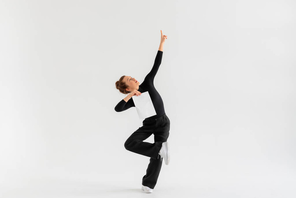 Young Girl, professional hip-hop dancer in a black clothes with blank white paper in the hand and performing over a Isolated white background with a plenty of copy space. - Фото, изображение