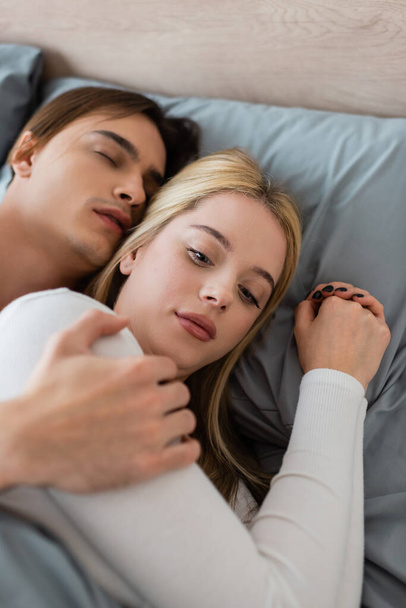 top uitzicht van shirtless man slapen en knuffelen verwarde vrouw na een nacht stand  - Foto, afbeelding