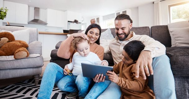 Family, tablet and kids learning online in the living room of their home with parents for child development. Education, video or internet with a father, mother and children sitting on the floor. - Photo, Image