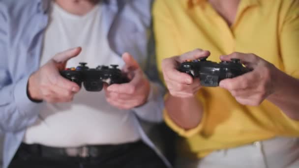 gepensioneerde hobby 's, oude man en vrouw hebben plezier met het vasthouden van joysticks in hun handen en het spelen van videospelletjes op console, close-up - Video