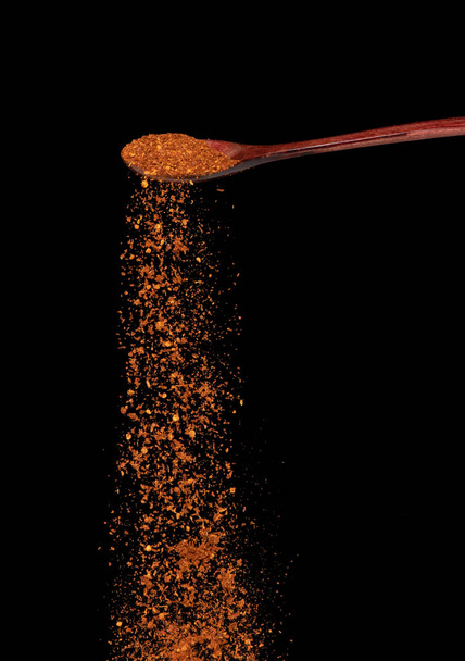 Red Hot Chilli fall, red grain chilli explode abstract cloud fly from wooden spoon. Beautiful complete seed chilly, food object design. Selective focus freeze shot black background isolated - Zdjęcie, obraz
