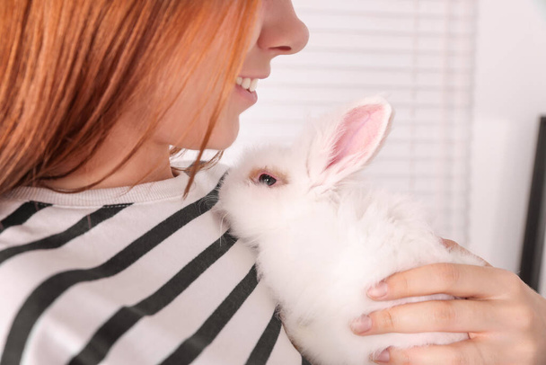 Woman with fluffy white rabbit indoors, closeup. Cute pet - Foto, imagen