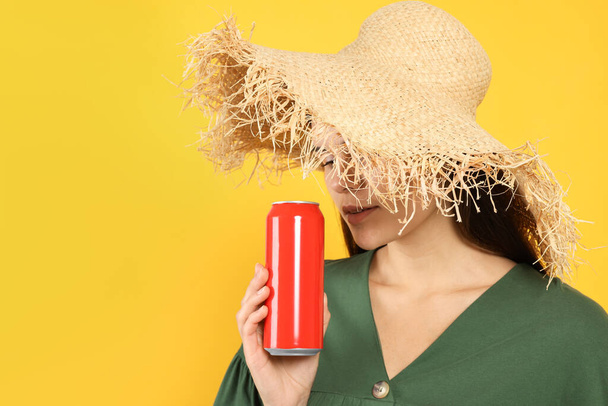 Woman in wicker hat holding red beverage can on yellow background - Foto, Imagem