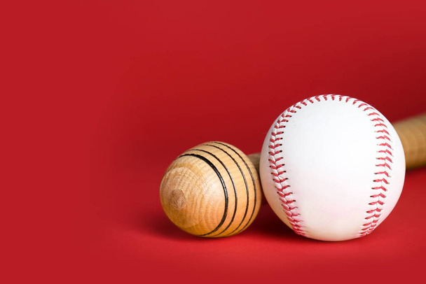 Wooden baseball bat and ball on red background, closeup. Space for text - Foto, Imagen