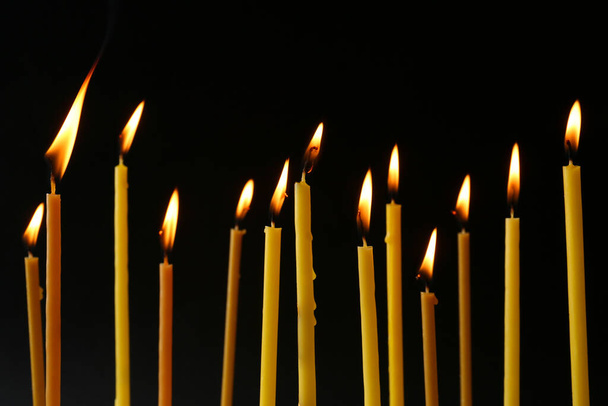 Burning candles on black background. Symbol of sorrow - Фото, зображення