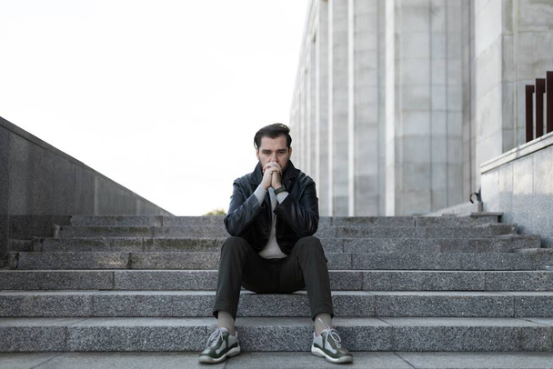 απογοήτευση ενός μεσήλικα Ευρωπαίου που κάθεται στα σκαλιά ενός κτιρίου. - Φωτογραφία, εικόνα