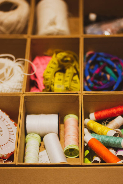 Needlework set in brass box. Multicolored skeins of thread in a cardboard. or wooden box. Hobby, sewing, crafts. Thread for clothes repair selective focus. Retro vintage colors. - Foto, Imagen