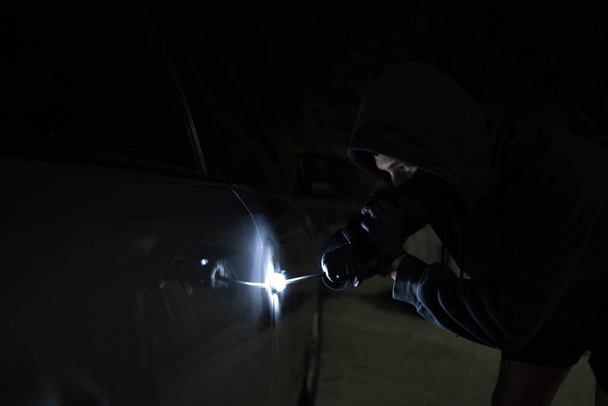 Man in black trying to steal a car. Car theft concept. - Photo, Image